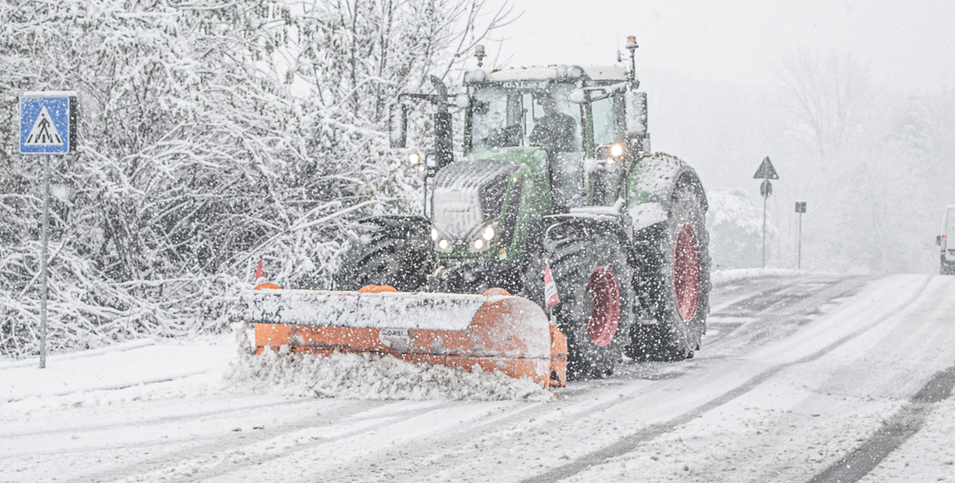 En traktor snöröjer i en snöstorm.