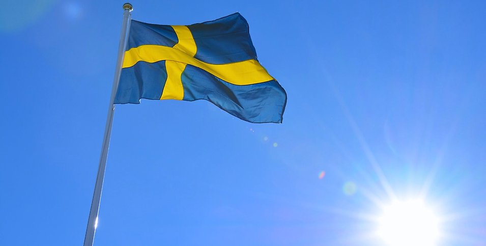 Blå himmel, en skinande sol och den svenska flaggan är hissad.