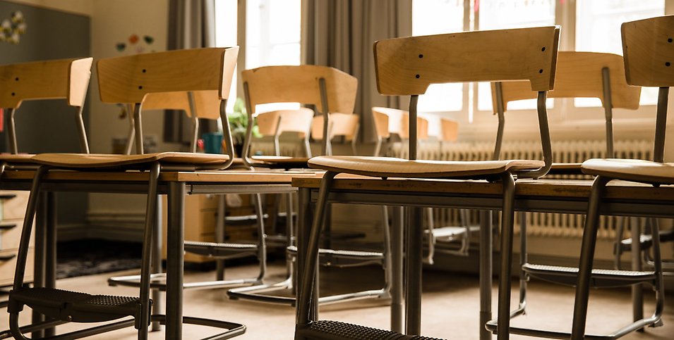 Ett klassrum med upphängda stolar på borden.