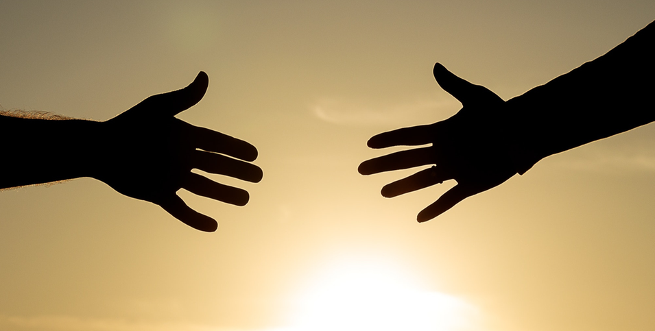Händer som möts i en solnedgång.